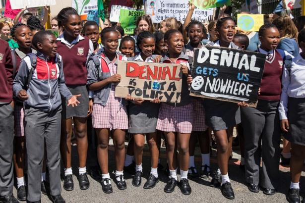 South African school children hold placards denouncing climate crisis denialism.