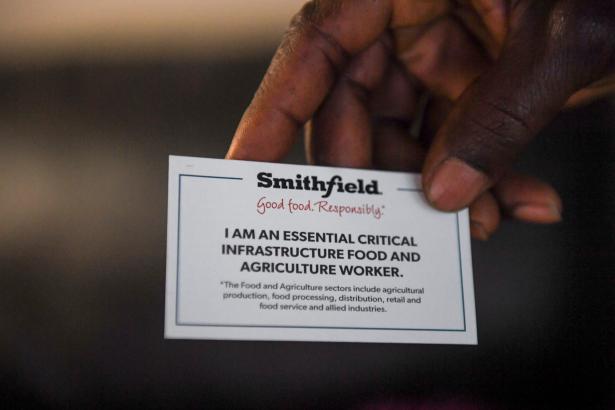 A worker's Smithfield ID saying essential worker being held by a hand 