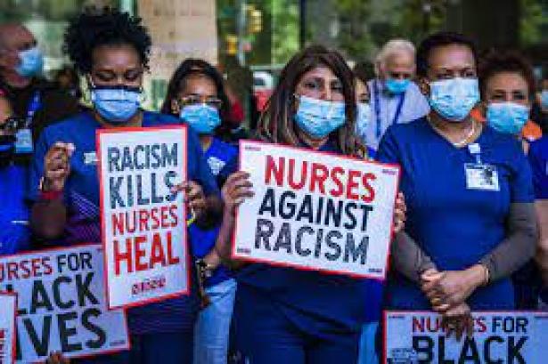 Nurses in masks and blue uniforms with signs - Nurses Against Racism