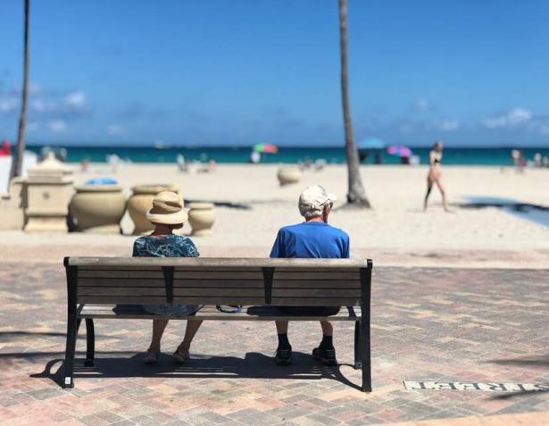 retirees sitting on a bench at the beach