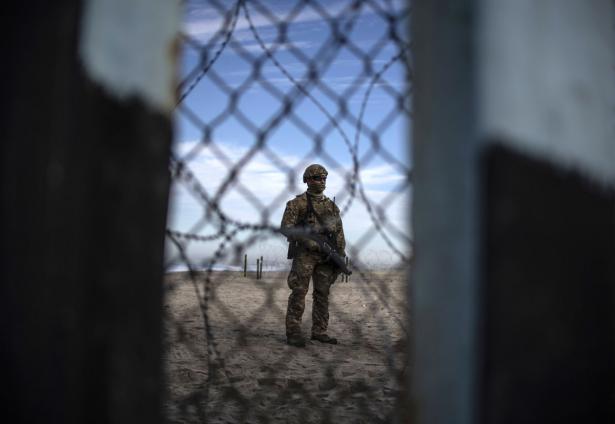 Armed US soldier standing at border with Mexico