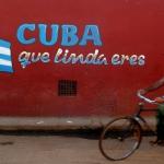 Cuban bicycle rider passing a mural