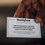 A worker's Smithfield ID saying essential worker being held by a hand 