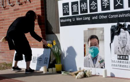 Women places a flower next to a photo of  Dr. Li Wenliang  