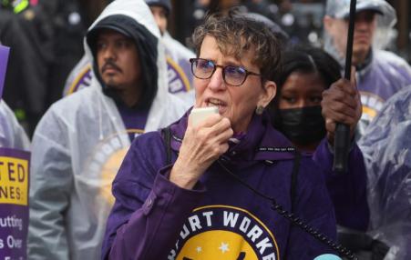 Union President speaking into a cell phone in the foreground with members behind her.