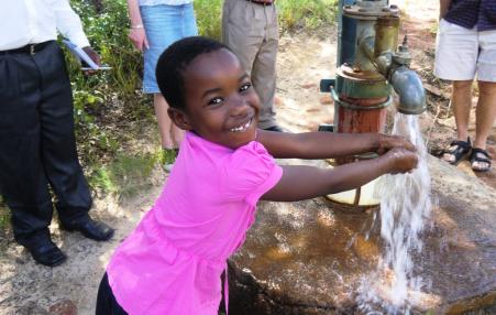 A young girl practices hand washing in Zimbabwe. 