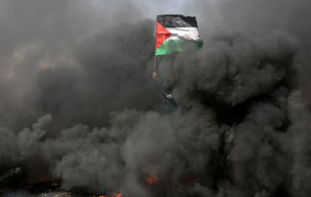 waving Palestinian flag in midst of black smoke