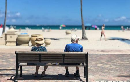 retirees sitting on a bench at the beach